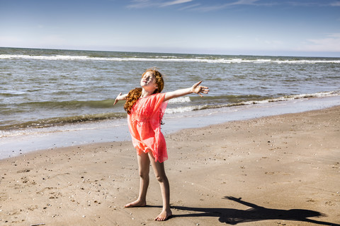 Niederlande, Zandvoort, Mädchen mit ausgestreckten Armen am Strand stehend, lizenzfreies Stockfoto