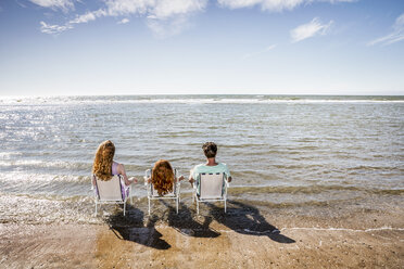 Niederlande, Zandvoort, Familie sitzt auf Stühlen im Meer - FMKF04376