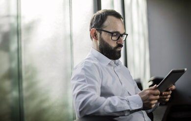 Businessman reading on digital tablet, looking woried - JOSF01338