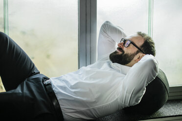 Businessman lying on window sill, taking a break - JOSF01346