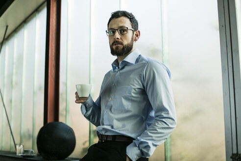 Geschäftsmann im Büro trinkt Kaffee - JOSF01350