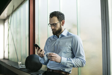 Busy businessman in office using smartphone - JOSF01351