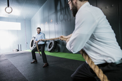 Two businessmen in gym doing tug of war - JOSF01362