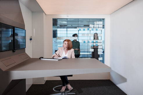 Geschäftsfrau arbeitet in einem futuristischen Büro und schaut auf einen Bildschirm - ZEF14306