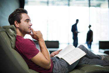 Man in office sitting in armchair, reading a book - ZEF14336