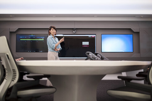 Geschäftsfrau steht vor einem Monitor in einem futuristischen Büro - ZEF14404