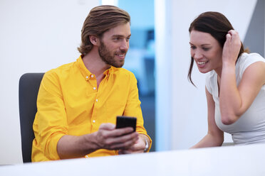 Geschäftsleute, die im Büro sitzen, sich unterhalten und ihr Smartphone benutzen - ZEF14406