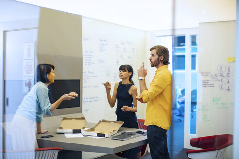 Geschäftsleute in einem futuristischen Büro, die eine Besprechung abhalten und Pizza essen - ZEF14409