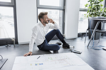 Businessman on the phone sitting on the floor of his office - DIGF02684