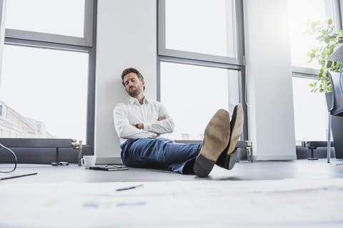 Geschäftsmann entspannt sich auf dem Boden seines Büros, lizenzfreies Stockfoto