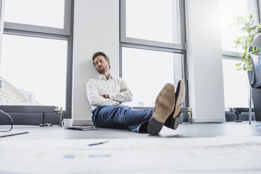 Businessman relaxing on the floor of his office - DIGF02686