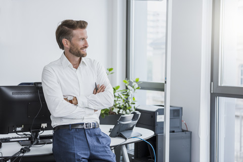 Portrait of smiling businessman with arms crossed in the office stock photo