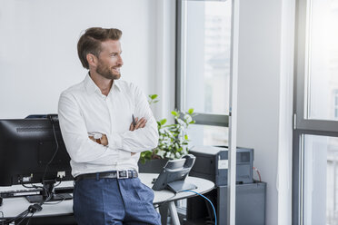 Porträt eines lächelnden Geschäftsmannes mit verschränkten Armen im Büro - DIGF02687