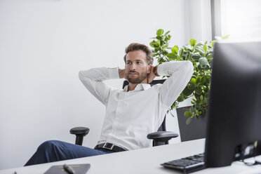 Portrait of businessman relaxing at desk in his office - DIGF02690