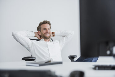 Portrait of content businessman relaxing at desk in his office - DIGF02691