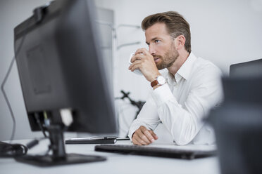 Porträt eines seriösen Geschäftsmannes, der am Schreibtisch im Büro sitzt und Kaffee trinkt - DIGF02696