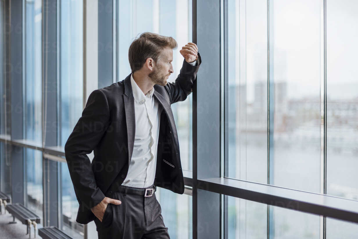 Businessman Standing In Office Looking Out Of The Window Stock Photo