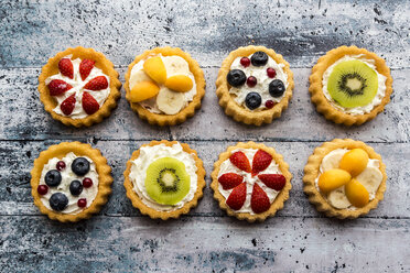 Eight mini pies with whipped cream garnished with different fruits - SARF03355