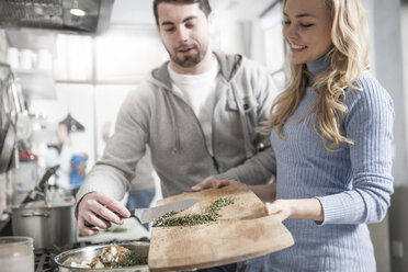 Couple helping one another moving spices in pot - ZEF14418