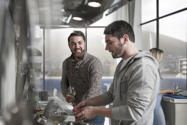 Friends with wine glasses preparing a meal in kitchen - ZEF14425