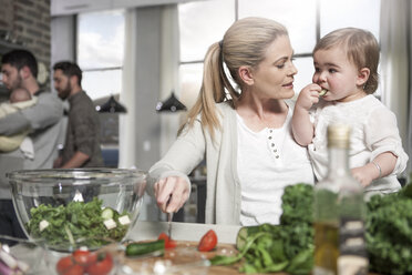 Mother holding baby preparing a healthy meal in kitchen - ZEF14431