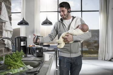 Vater mit Headset macht Kaffee in der Küche und hält sein Baby - ZEF14438