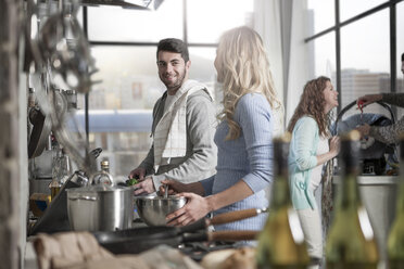 Ehepaar bereitet Essen in der Küche mit Familie im Hintergrund vor - ZEF14443