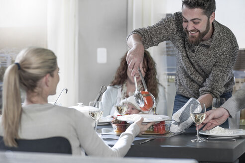 Mann serviert Essen an Freunde am Tisch - ZEF14460