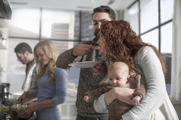 Family and friends preparing a meal in kitchen - ZEF14477