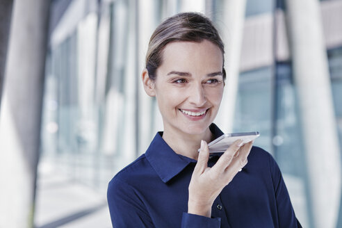Porträt einer lächelnden Geschäftsfrau, die ein Mobiltelefon benutzt - RORF00989