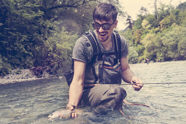Slowenien, Mann beim Fliegenfischen im Soca-Fluss beim Fangen eines Fisches - BMAF00311