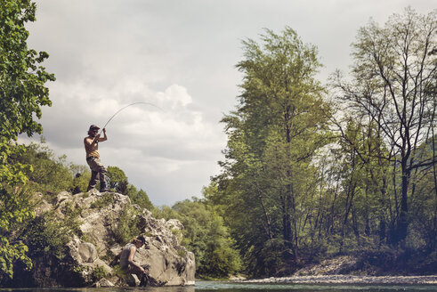 Slowenien, Mann beim Fliegenfischen im Soca-Fluss auf einem Felsen stehend - BMAF00314