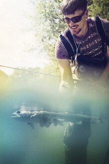 Slovenia, man fly fishing in Soca river catching a fish - BMAF00315