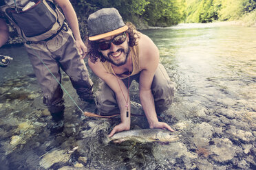 Slowenien, zwei Männer beim Fliegenfischen im Soca-Fluss, die einen Fisch fangen - BMAF00320