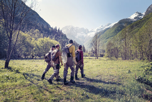 Slovenia, Bovec, four anglers walking on meadow towards Soca river - BMAF00332