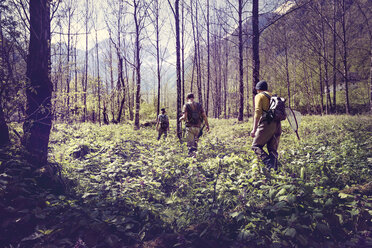 Slovenia, Bovec, three anglers walking in forest towards Soca river - BMAF00335