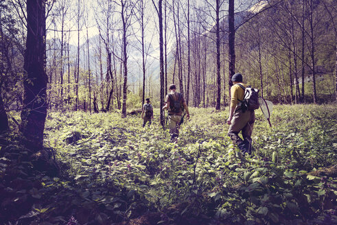 Slovenia, Bovec, three anglers walking in forest towards Soca river - BMAF00335