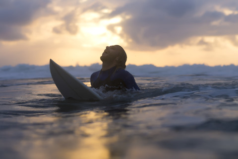 Indonesia, Bali, surfer in the ocean at sunrise stock photo