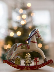 Nostalgic deocrative rocking horse before a lit Christmas tree - MELF00184