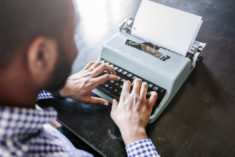 Nahaufnahme eines Mannes am Schreibtisch mit Schreibmaschine, lizenzfreies Stockfoto