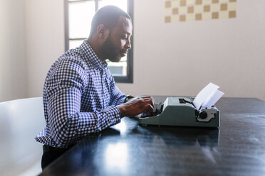 Young man at desk using typewriter - GIOF03139