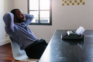 Young man at desk with typewriter having a break - GIOF03140