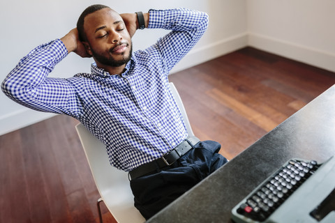 Young man at desk with typewriter having a break stock photo