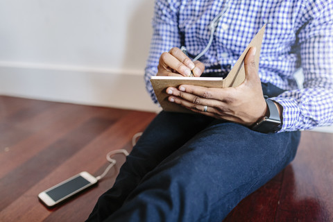 Man sitting on the wooden floor writing a note stock photo