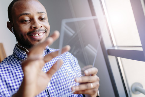 Lächelnder junger Mann, der ein futuristisches Tablet benutzt, lizenzfreies Stockfoto