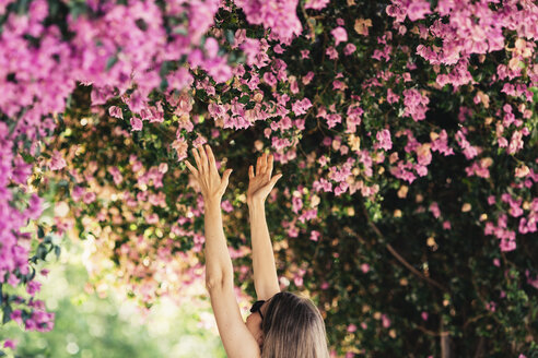 Frau greift nach rosa Blüten im Park - JPF00270