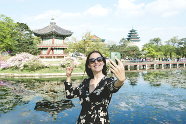 South Korea, Seoul, Woman taking a selfie with smartphone at Gyeongbokgung Palace - GEMF01765