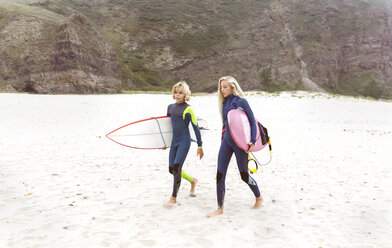 Spanien, Aviles, zwei junge Surfer gehen am Strand spazieren - MGOF03546