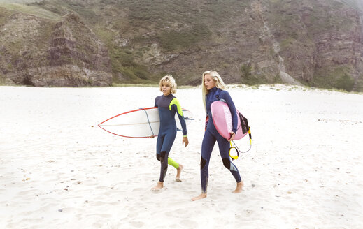 Spanien, Aviles, zwei junge Surfer gehen am Strand spazieren - MGOF03546