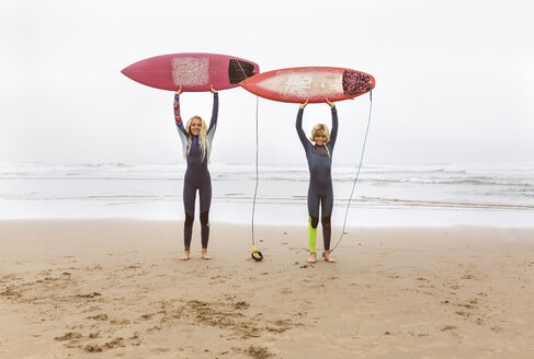 Spanien, Aviles, zwei junge Surfer am Strand mit ihren Surfbrettern - MGOF03554